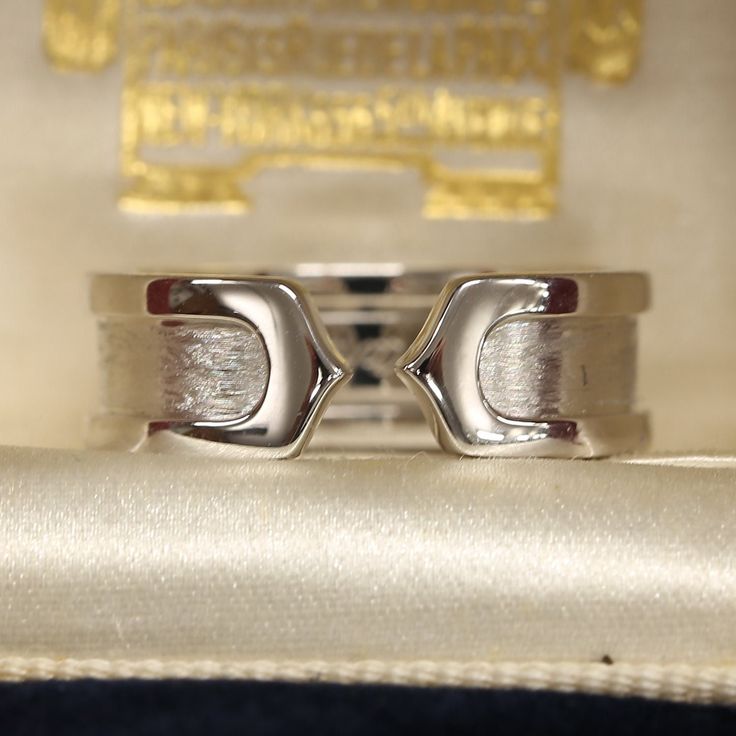 This is a beautiful ring from the luxury jewellery designer Cartier. The ring forms part of the 'Double C' collection and is an iconic and highly recognisable design. The 18ct white gold has a brushed finish in the centre and polished gold borders. Condition: Used (Very Good) Weight: 6.8 grams Ring Size: K 1/2 (50) Band Width: 6.5mm Marked: 'Cartier' '2000' '750' '50' and the serial number Box: Plain gift box Certificate: The Vintage Jeweller guarantee of authenticity If you have any questions r Timeless Polished Promise Band, Modernist White Gold Signet Ring For Formal Occasions, Timeless Promise Band With Polished Finish, Modern Platinum Rings For Gift, Modern Polished Finish Rings For Anniversary, Modern Platinum Rings For Gifts, Modern Platinum Signet Ring For Gift, Modern Platinum Signet Ring As Gift, Modernist Open Signet Ring For Formal Occasions