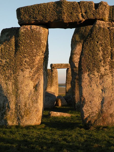 an arch in the middle of a grassy area with rocks and grass on either side