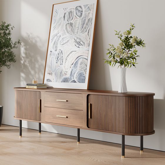 a wooden cabinet with two drawers next to a potted plant and a framed print on the wall