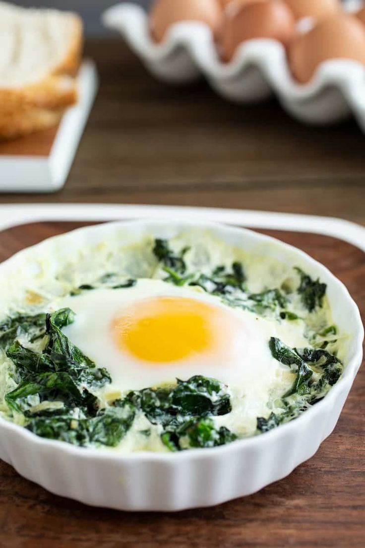 an egg in a bowl with spinach and bread