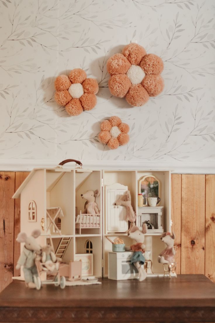 two teddy bears sitting on top of a wooden table in front of a wallpapered wall