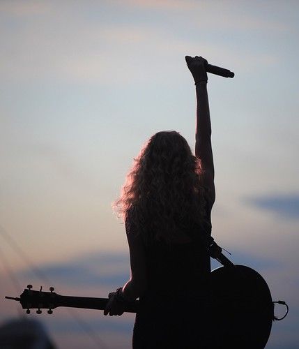 a woman holding a guitar up in the air