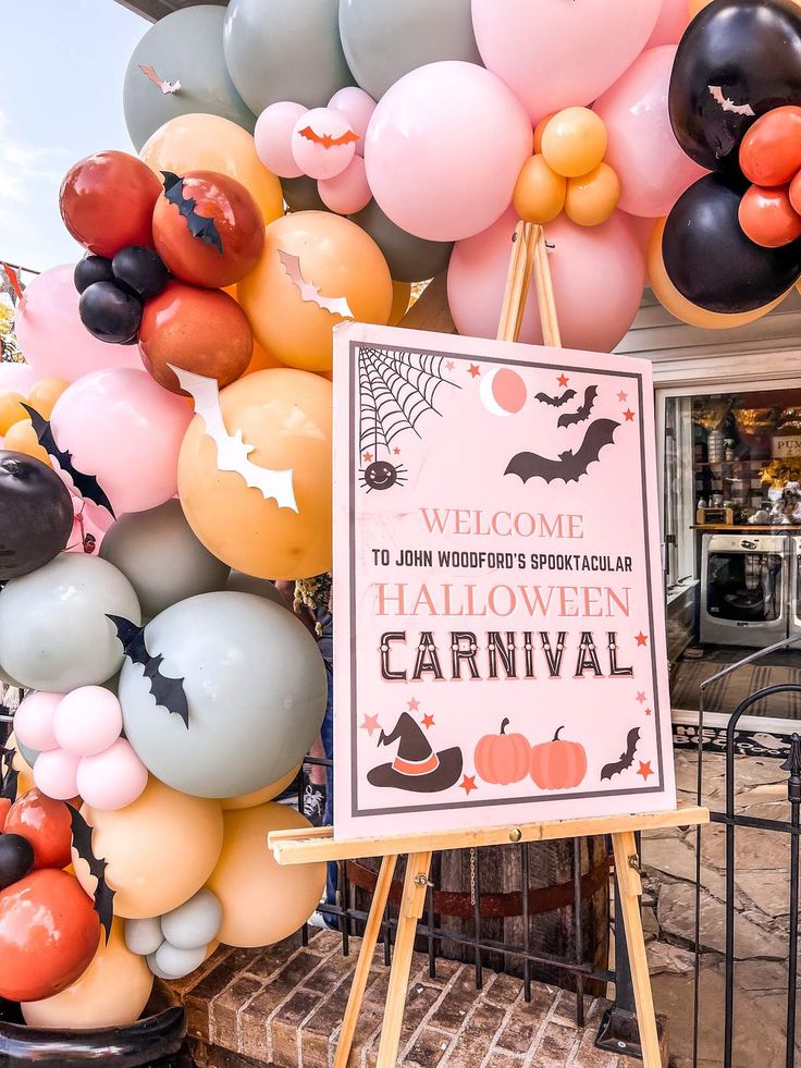 a halloween party with balloons and decorations on the front porch, including a sign that says happy halloween carnival