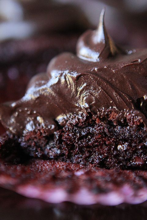 a piece of chocolate cake sitting on top of a purple and white plate covered in frosting