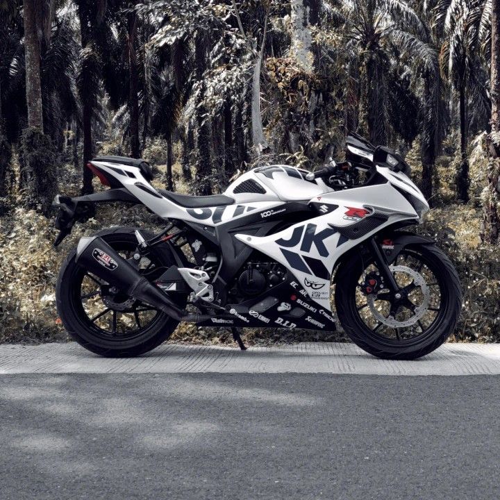 a white and black motorcycle parked next to some trees