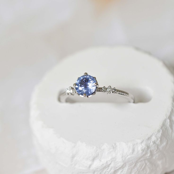 Discover the perfect symbol of love and commitment with our magical pastel blue sapphire engagement ring. The 0.75 carat blue sapphire sits elegantly in a solitaire setting, surrounded by 8 round prongs and set on a 14k white gold band with two sets of 3 round graduated side diamonds add the perfect touch of sparkle to this beautiful and elegant design. Make your proposal unforgettable with this timeless piece. Sapphire Solitaire Engagement Ring, Jewelry Organizer Stand, Light Blue Sapphire, Blue Sapphire Engagement Ring, Sapphire Solitaire, Solitaire Setting, Jewelry Display Stands, Sapphire Engagement Ring Blue, Sapphire Engagement Ring