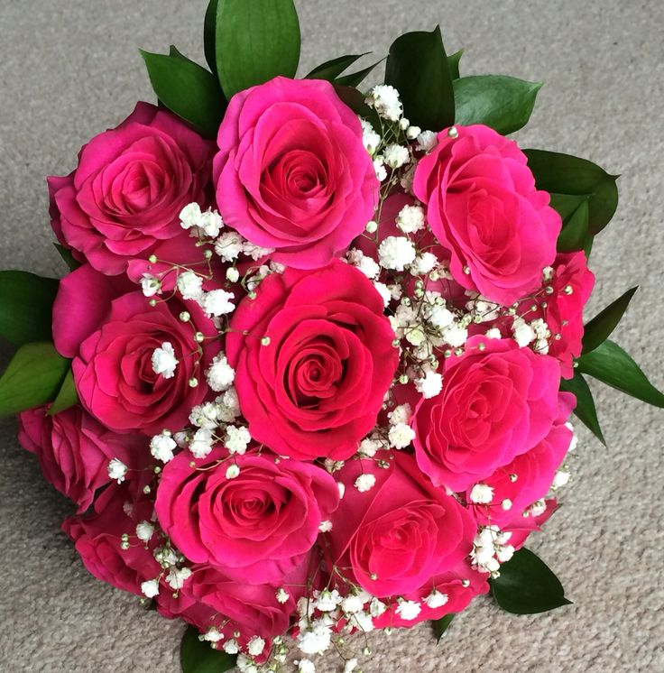 a bouquet of pink roses with baby's breath in the middle is laying on the floor