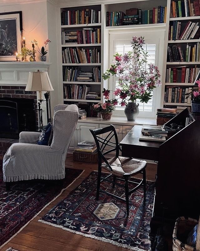 a living room filled with furniture and a fire place next to a book shelf full of books