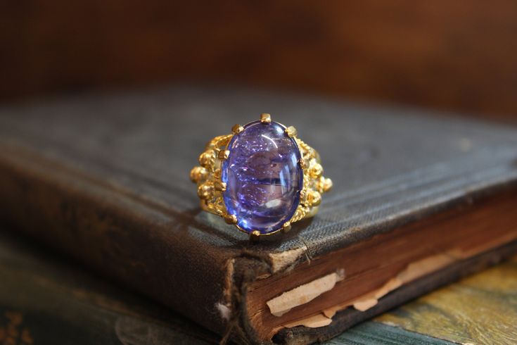 Welcome to The Onio Archives!    This listing is for an absolutely stunning 22k yellow gold tanzanite cabochon cocktail ring. This unique ring features a stunning 16 carat oval shaped tanzanite cabochon center stone. This gorgeous vintage ring is a size 7.5, weighs a total of 10g, and the stone measures approximately 20mm long by 15mm wide. Shop Notes   I'm a lawyer with a passion for all things vintage. After opening my vintage home goods shop on Etsy, The Onio Collection (check it out!) I deci Elegant Gold Amethyst Cabochon Ring, Exquisite Gold Amethyst Ring For Formal Occasions, Elegant Handmade Yellow Gold Amethyst Ring, Handmade Gold Amethyst Ring For Formal Occasions, Luxury Handmade Amethyst Ring For Formal Occasions, Faberge Jewelry, Dome Ring, Tanzanite Ring, Ring Oval