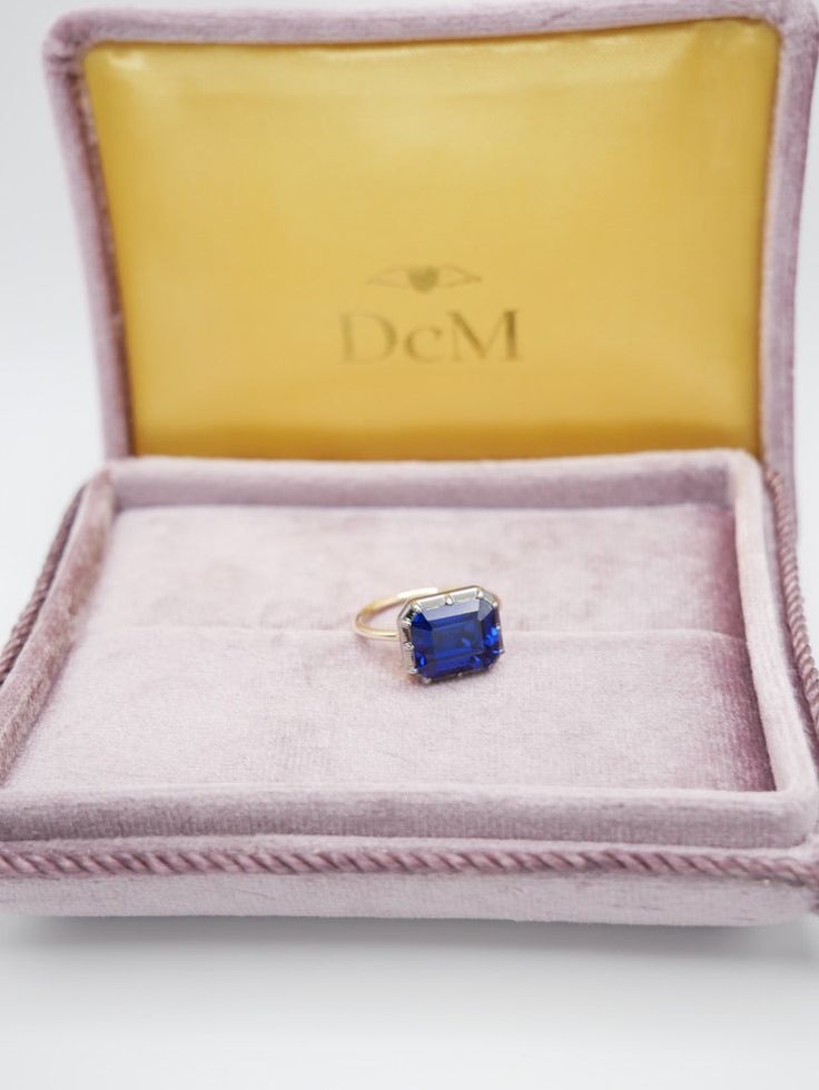 The Georgian-Victorian Emerald Cut Blue Sapphire & Blackened Gold East West Button Back Collet Ring—a timeless engagement piece inspired by the grace of the Georgian and Victorian periods. This ring photographed features a stunning 4 ct lab-grown sapphire in a Georgian cut-down collet setting and button back. It's not just an engagement ring; it's a versatile piece designed for stacking and layering with other styles. Lab Grown Gems: Our lab grown stones are not synthetic, or treated. These are Formal Sapphire Ring With Cushion Diamond Cut, Formal Sapphire Ring With Cushion Cut, Luxury Emerald-cut Sapphire Ring With 17 Jewels, Classic Sapphire Halo Ring, Classic Sapphire Birthstone Ring, Formal Sapphire Ring With Cushion Brilliant Cut, Formal Sapphire Ring With Brilliant And Cushion Cut, Classic Sapphire Baguette Cut Ring, Timeless Sapphire Ring With Diamond For Gift