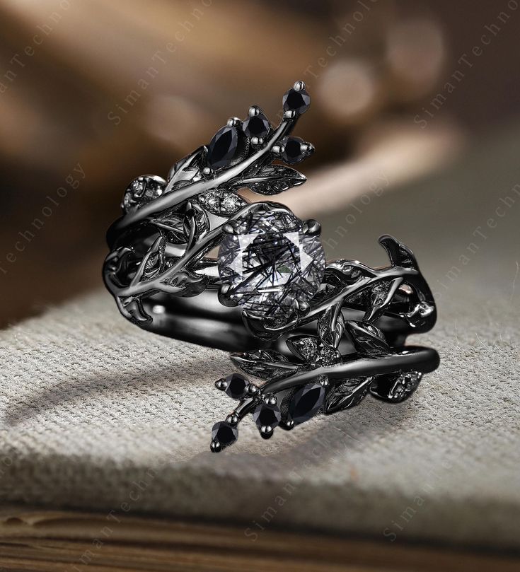 an intricately designed ring is shown on top of a piece of fabric with leaves