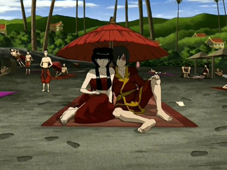 two people sitting on a rug with an umbrella over their heads in front of them