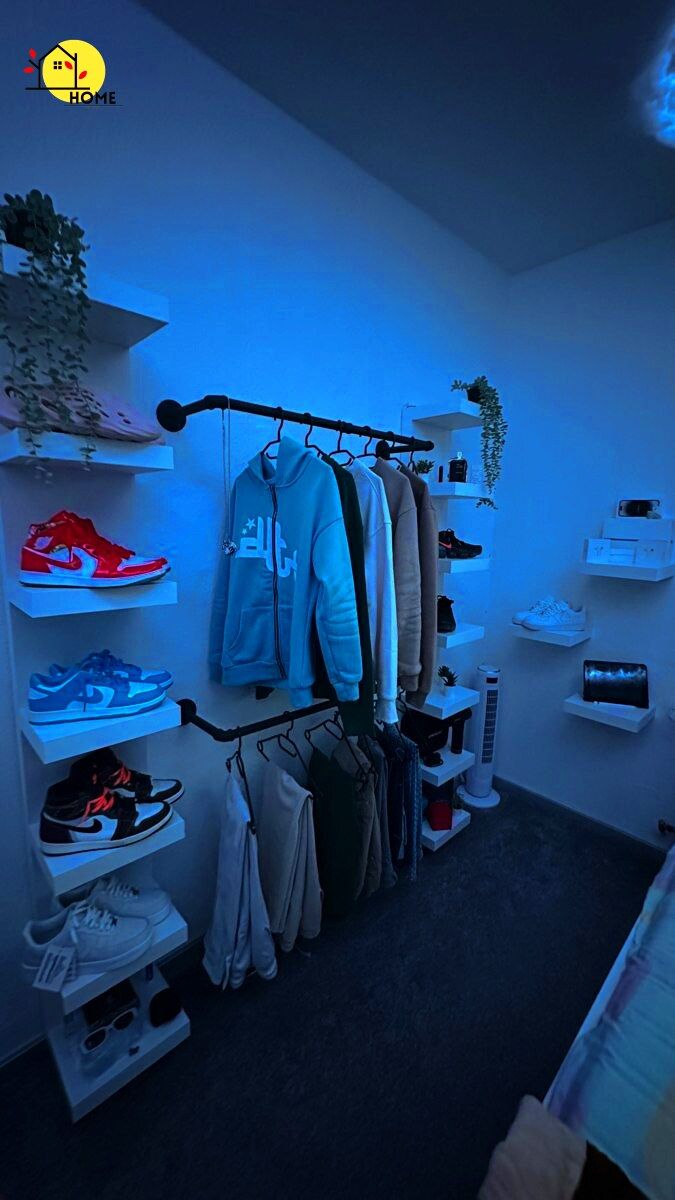 a bedroom with blue lighting and clothes hanging on the rack in front of the bed