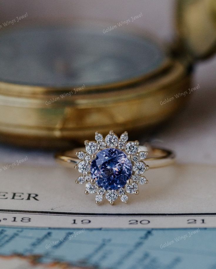 a blue diamond ring sitting on top of a piece of paper next to a magnifying glass