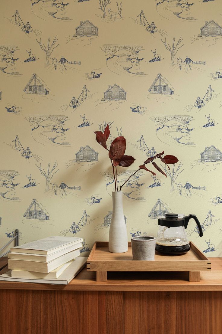 a wooden table topped with a vase filled with flowers next to a wallpapered wall