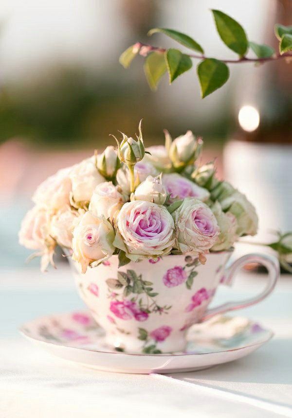 a teacup filled with flowers sitting on top of a table