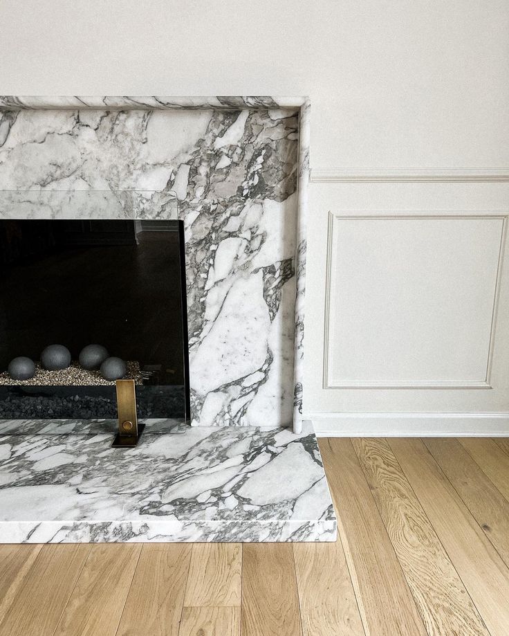 an empty room with a marble fireplace and wood floors