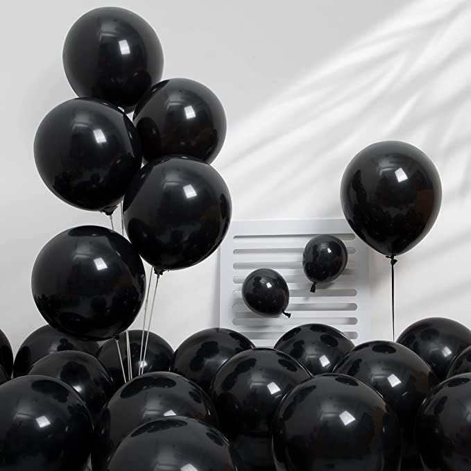 a bunch of black balloons are in front of a white wall and an old radio