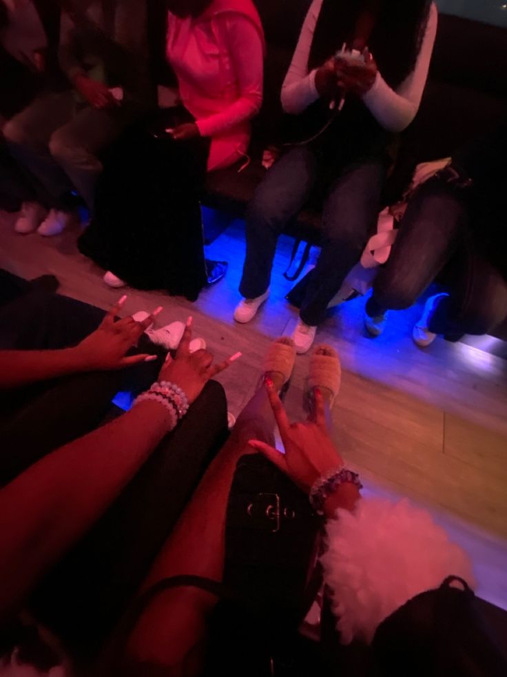 several people sitting on the floor with their feet up and one person holding something in her hand