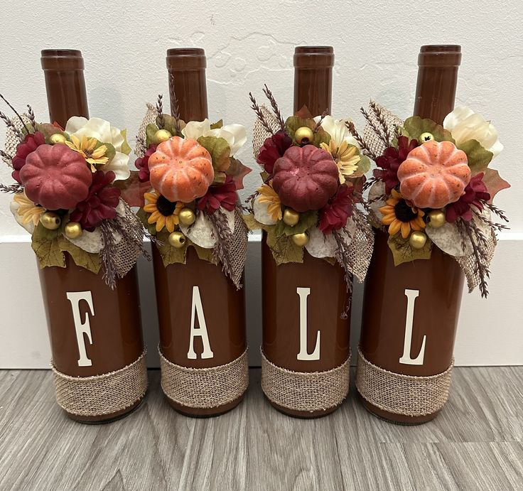 three brown wine bottles with fall decorations on them