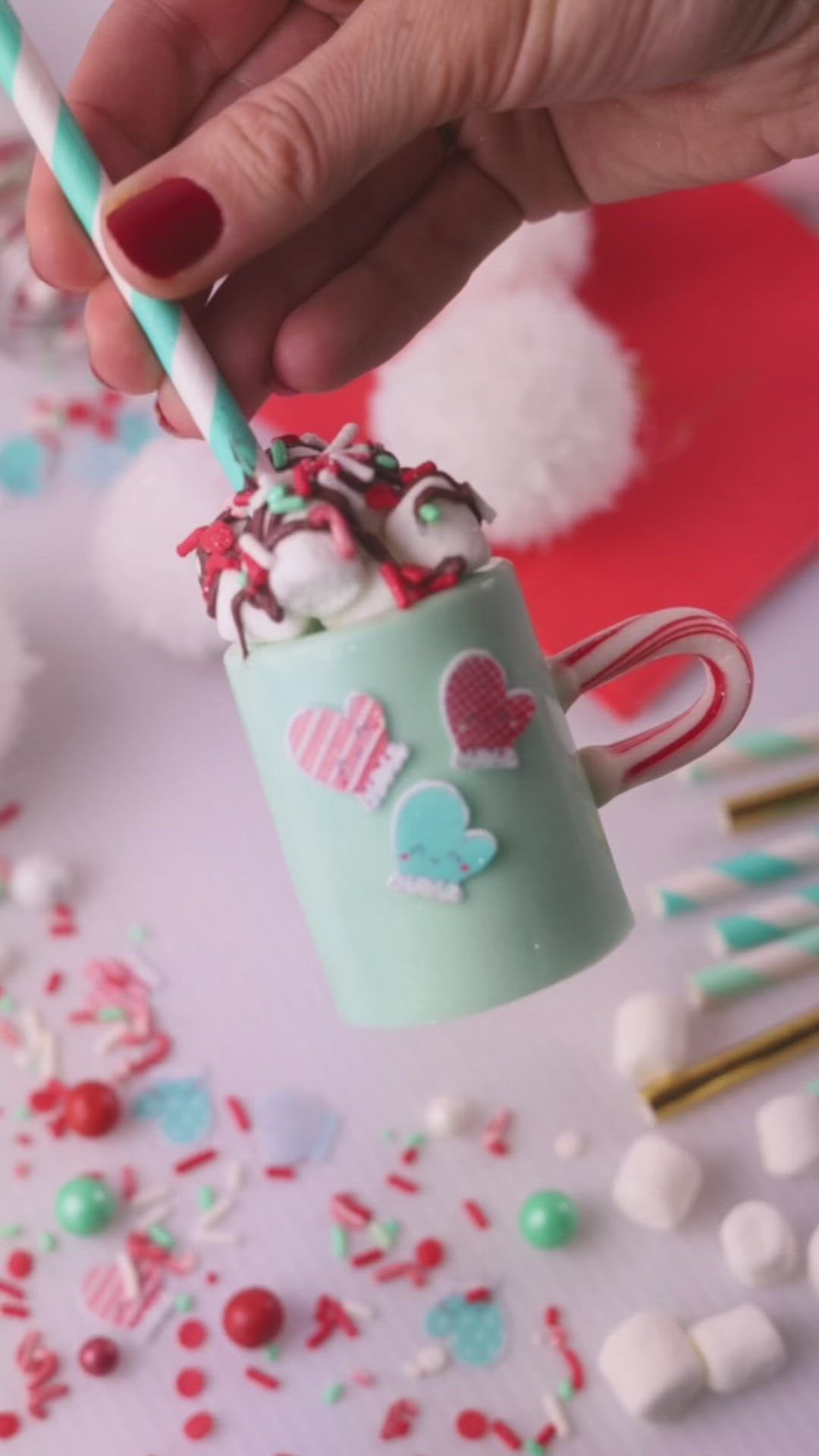 This may contain: someone is holding a candy cane in a cup with whipped cream and sprinkles