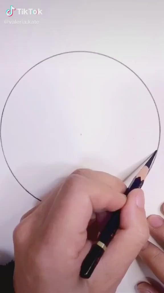 This may contain: someone is drawing a circle on paper with scissors