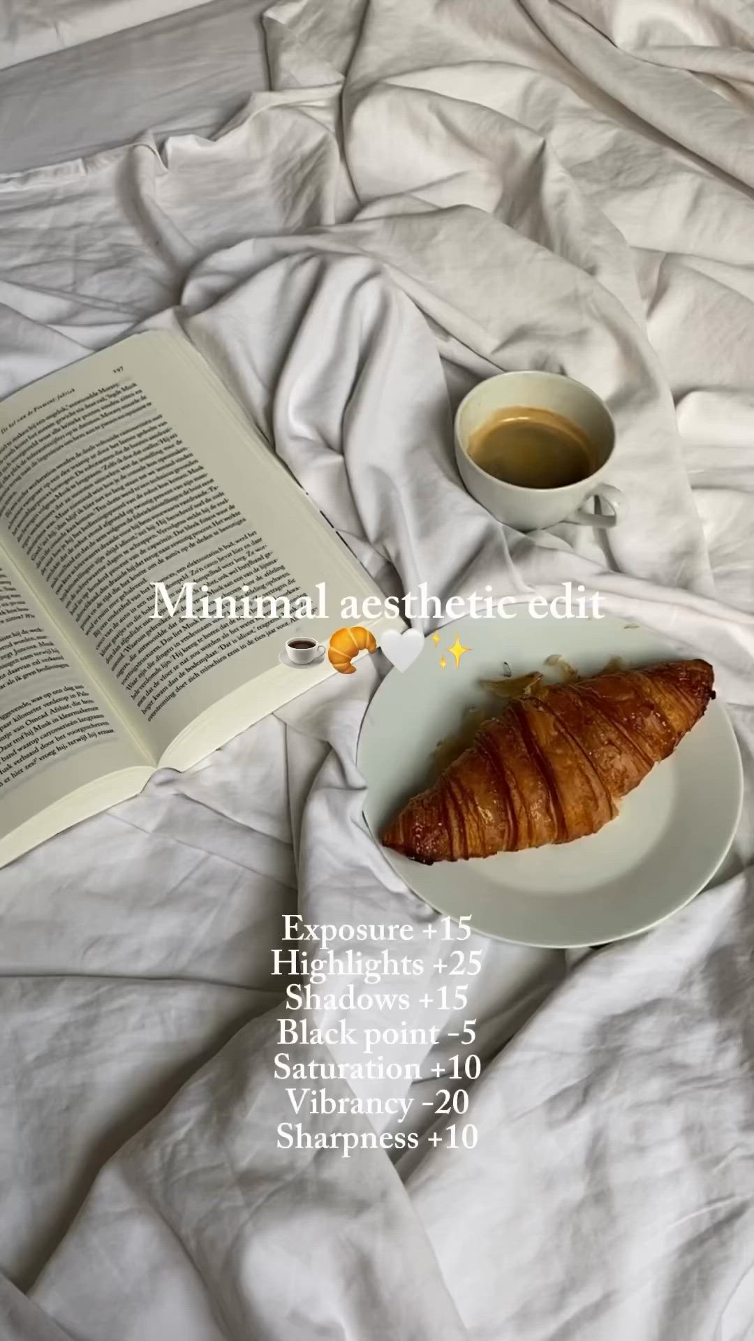 This may contain: an open book on a bed next to a cup of coffee and croissant