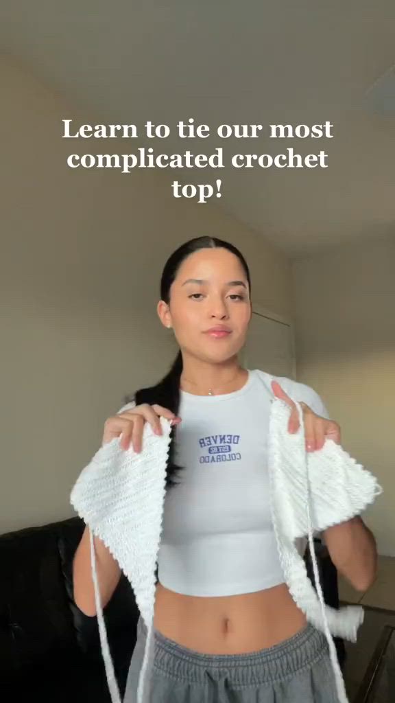 This may contain: a woman holding up a white shirt with the words learn to tie our most complicated crochet top