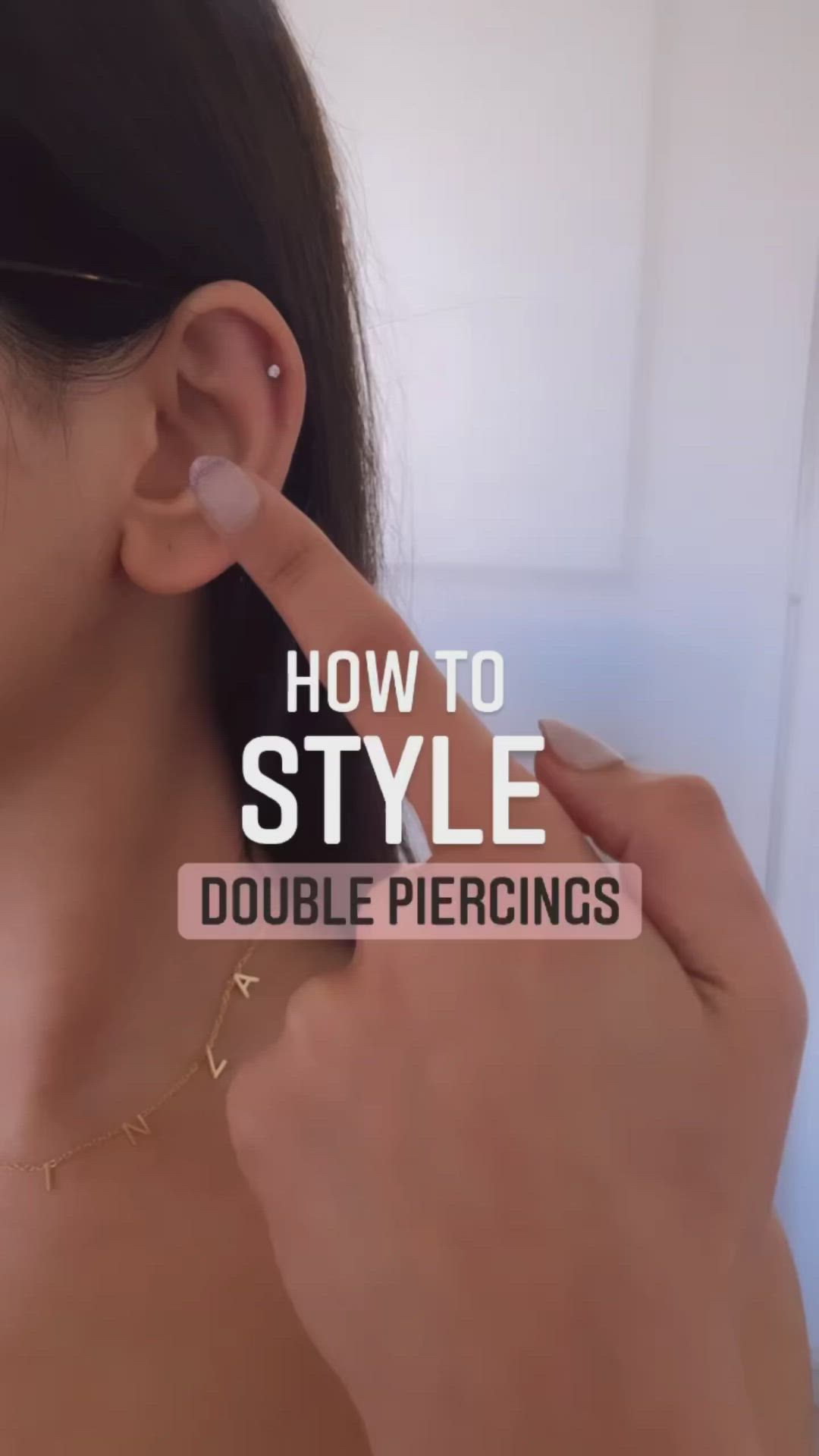 This may contain: a woman is touching her ear with the words how to style double piercings