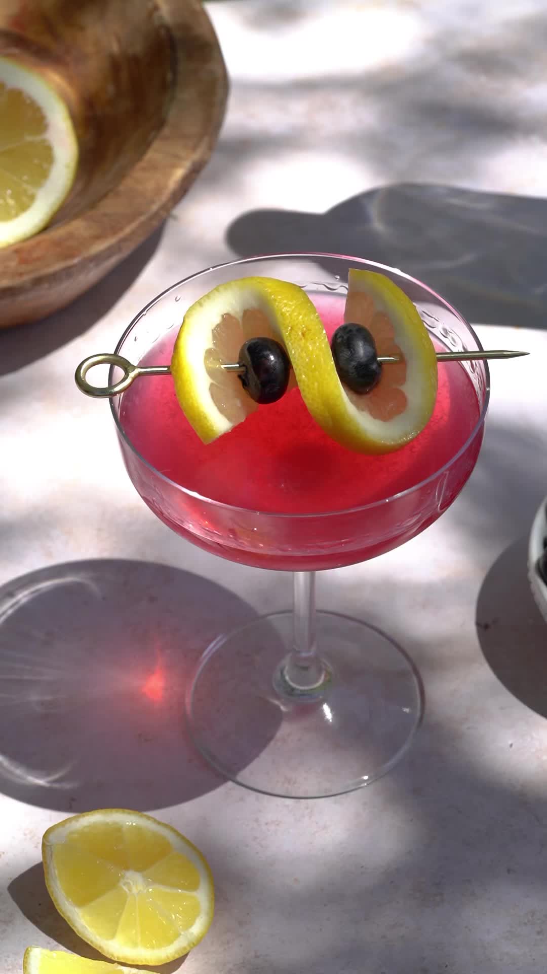 This may contain: a red drink with lemon slices and olives on the rim