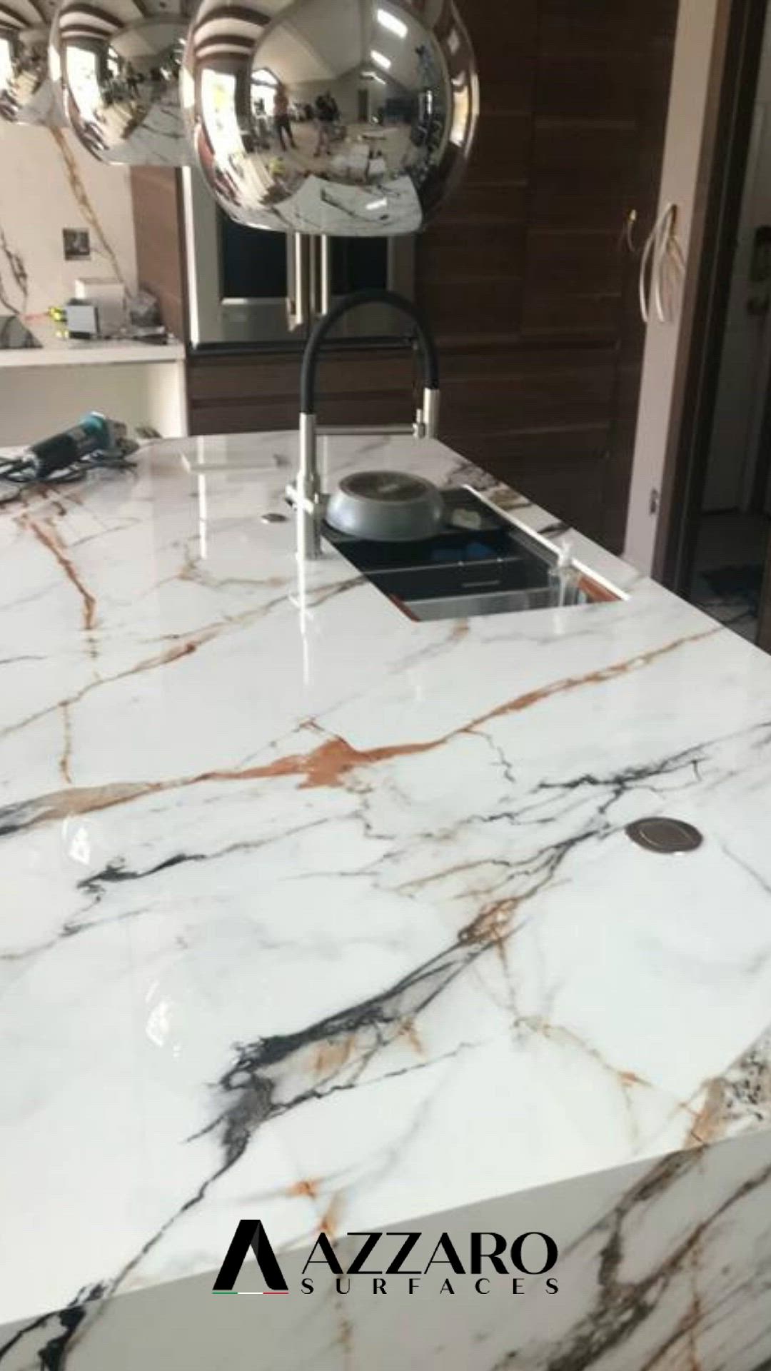 This may contain: a marble counter top in a kitchen with chrome balls hanging from it's sides