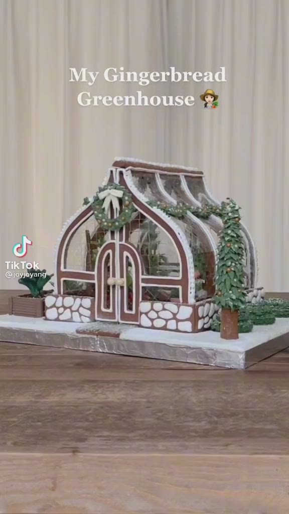 This may contain: a gingerbread house is sitting on a table with greenery around it and the words, my gingerbread greenhouse