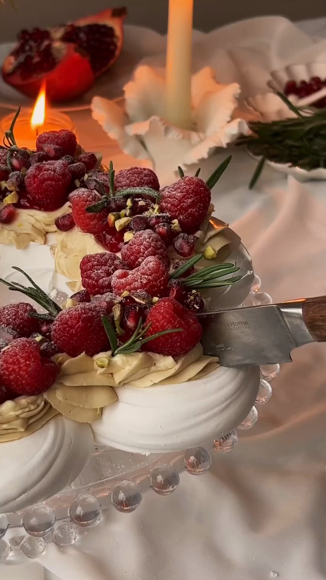 This may contain: a cake with raspberries and whipped cream is on a plate next to candles