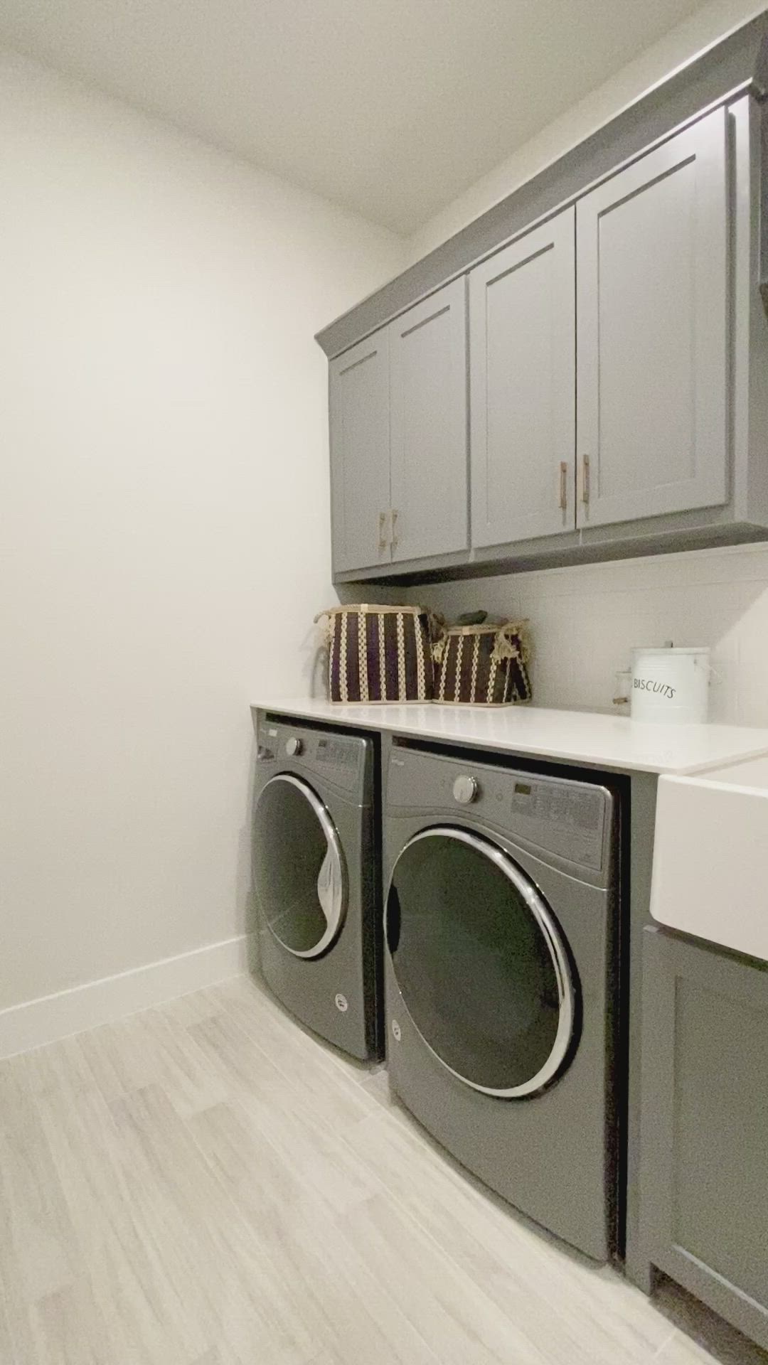 This may contain: a washer and dryer in a laundry room with cabinets on the wall above them