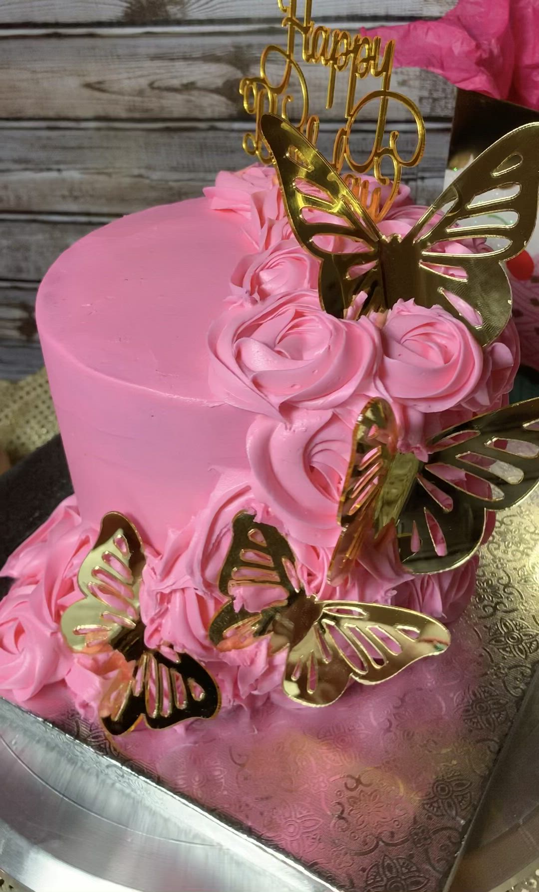 This may contain: a pink cake decorated with gold butterflies and the words happy birthday on it's top