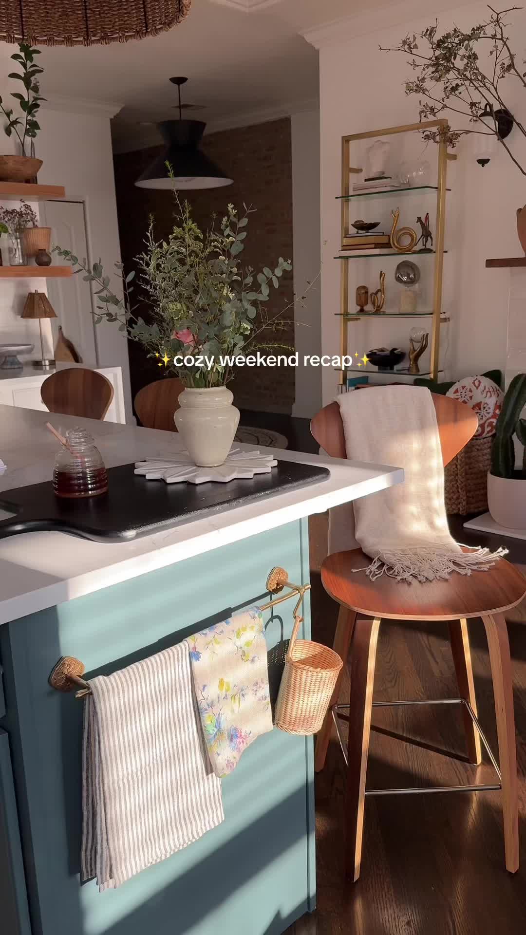 This may contain: a kitchen island with two chairs and a potted plant