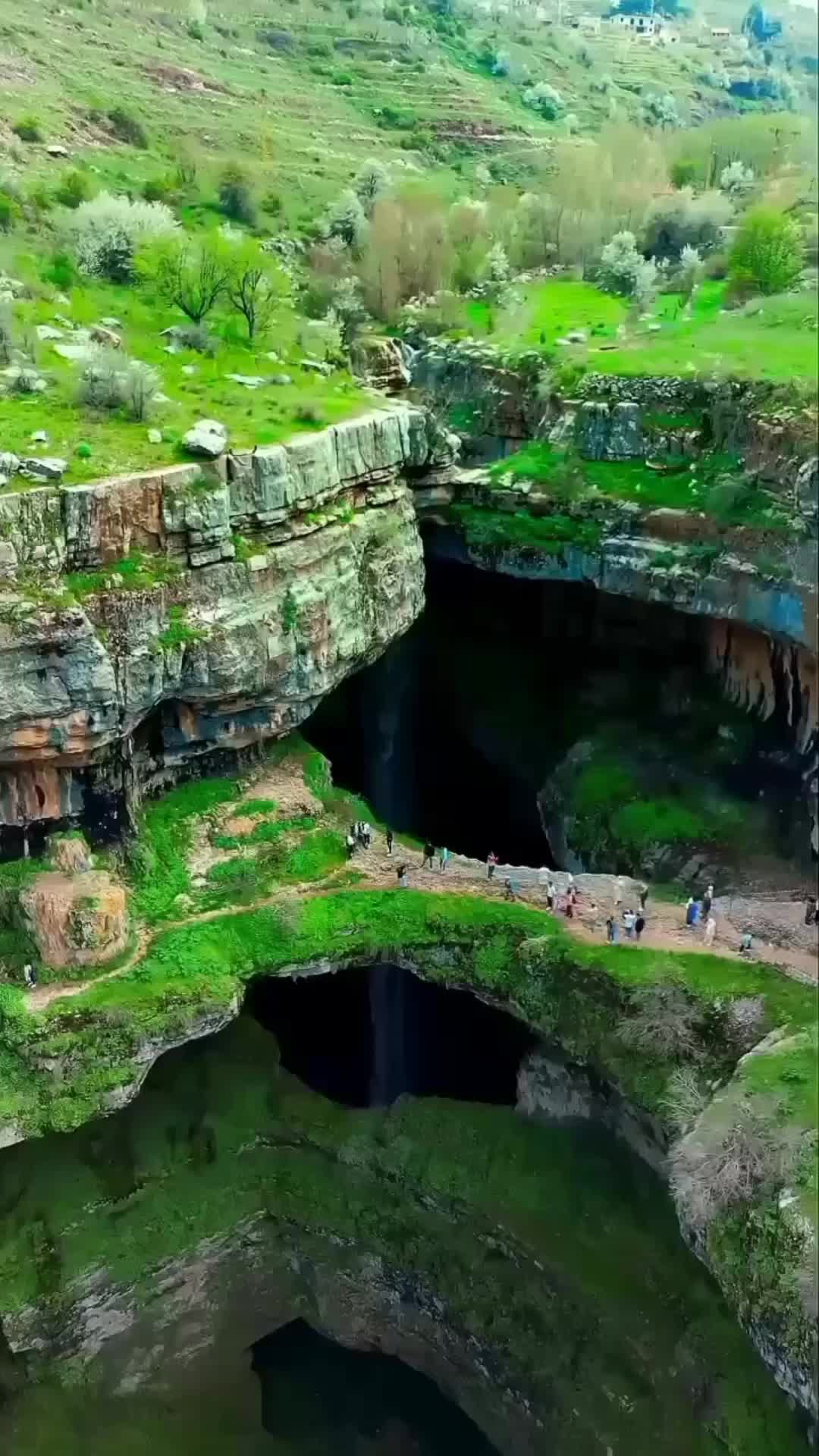 This may contain: people are standing at the entrance to a cave