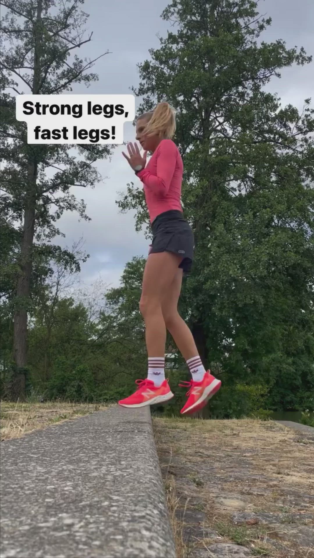 This may contain: a woman in pink shirt and black shorts standing on sidewalk next to trees with text reading strong legs, fast legs