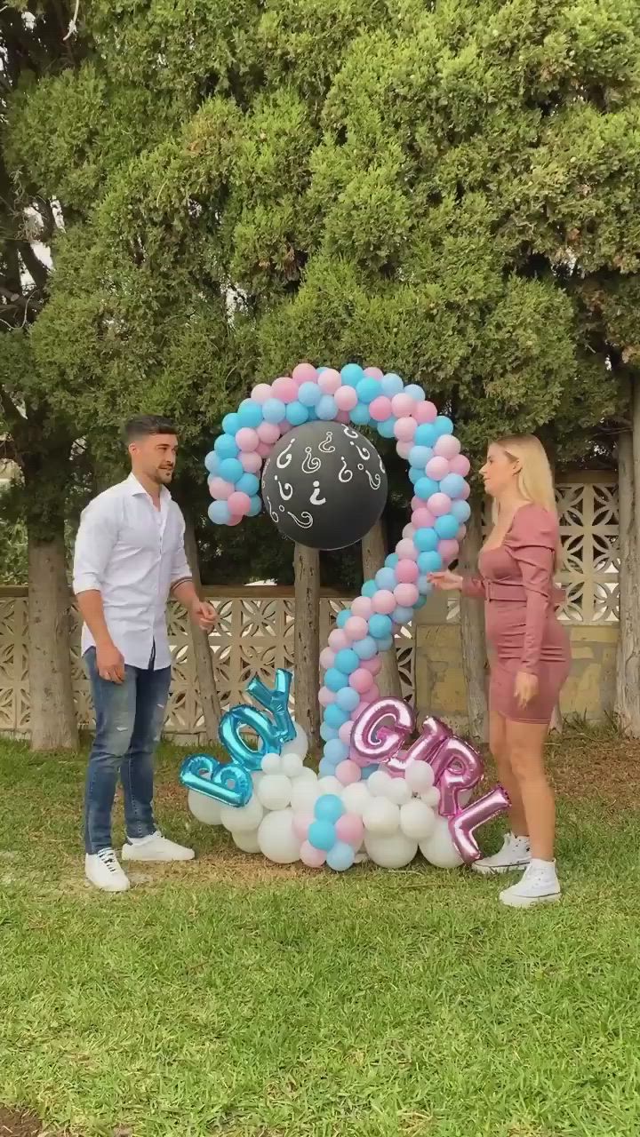 This may contain: a man and woman standing next to each other in front of a number 2 balloon arch