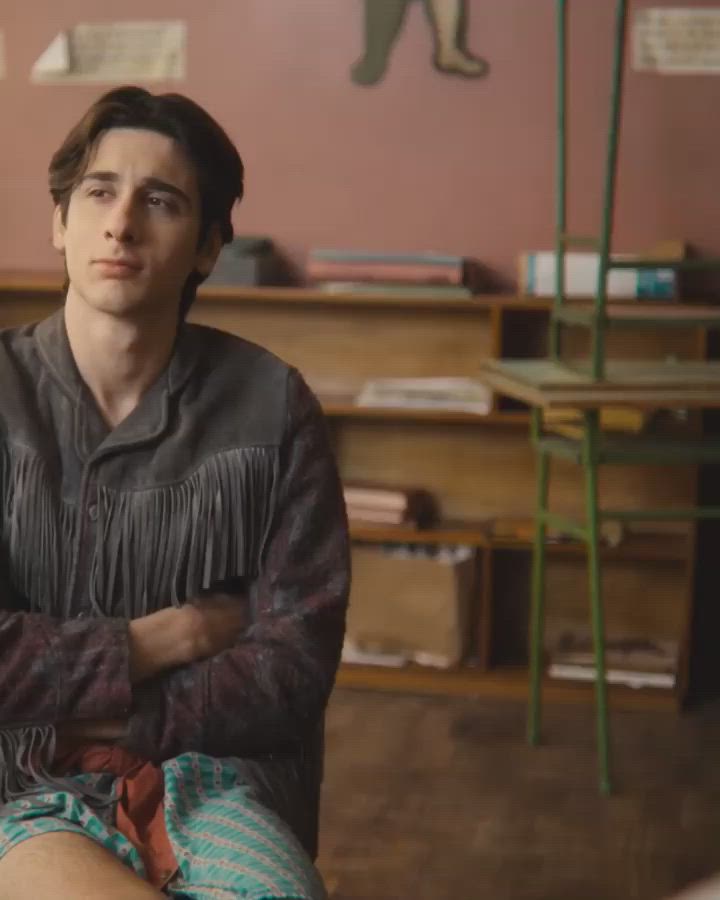 This may contain: a young man sitting on the floor in front of a desk with his arms crossed