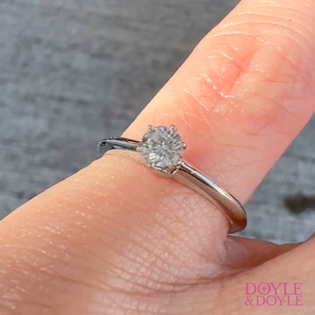 This may contain: a woman's hand with a diamond ring on top of her finger, showing the center stone