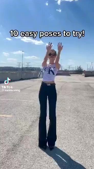 This may contain: a woman is standing in the middle of an empty parking lot with her arms up