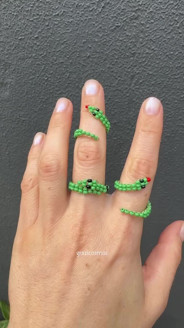 This may contain: a woman's hand with green string wrapped around the middle of her fingers and two rings on each finger