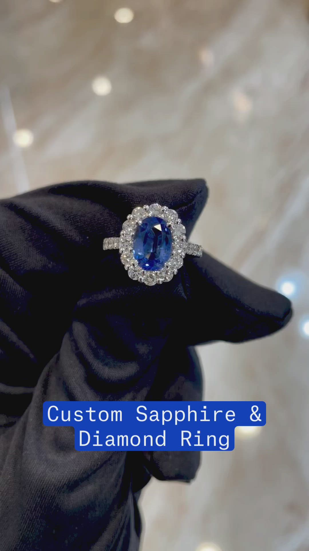 This may contain: a person wearing a black glove holding a ring with a blue stone in it and the words custom sapphire & diamond ring