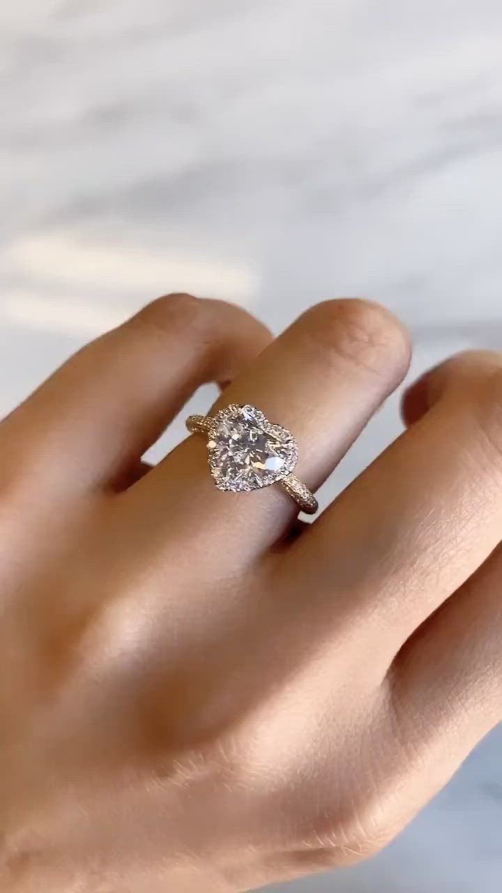 This may contain: a woman's hand holding an engagement ring with a diamond in the middle, on a marble surface