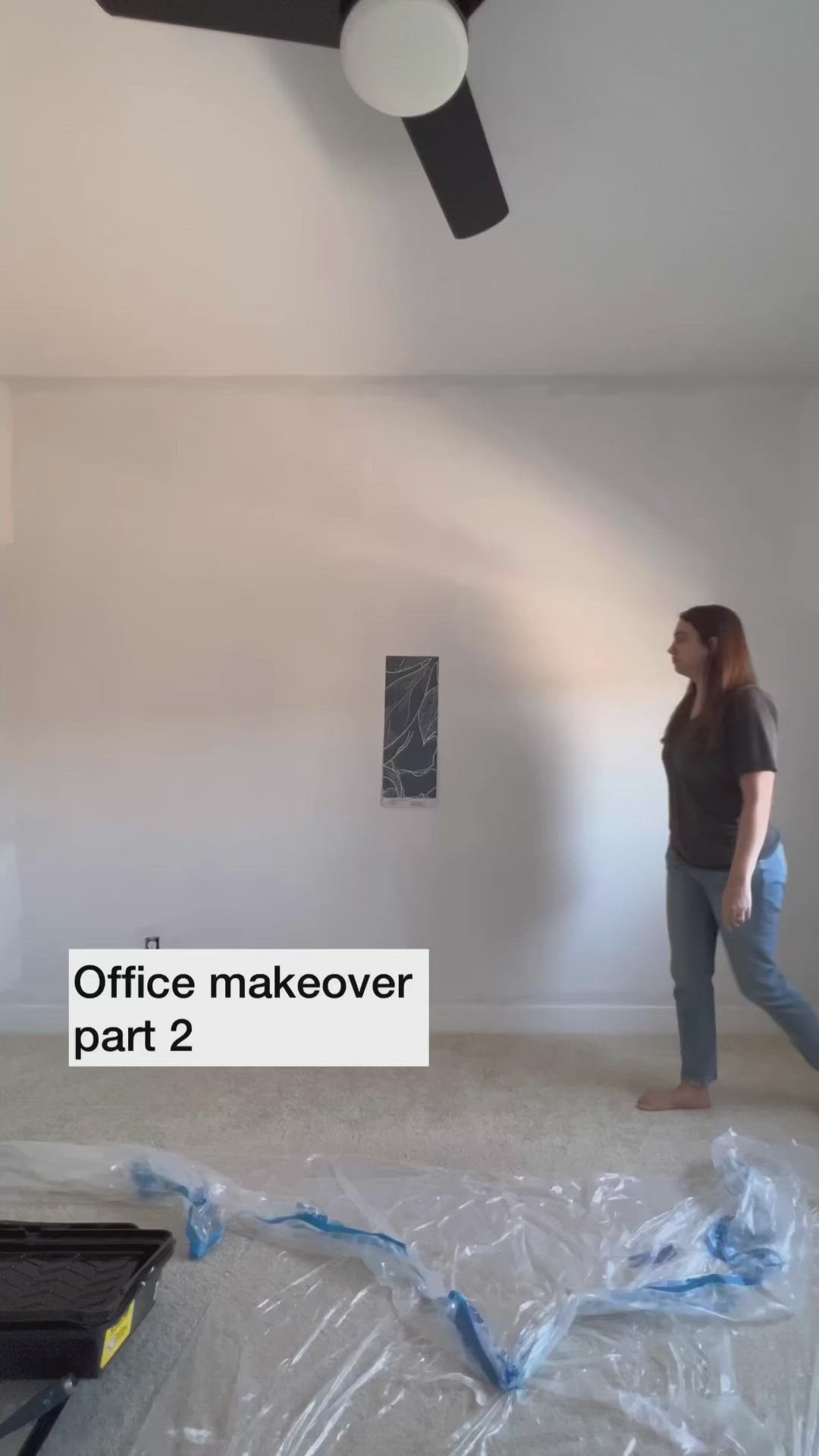 This may contain: a woman is standing in the middle of a room that has been painted white with blue tape on it