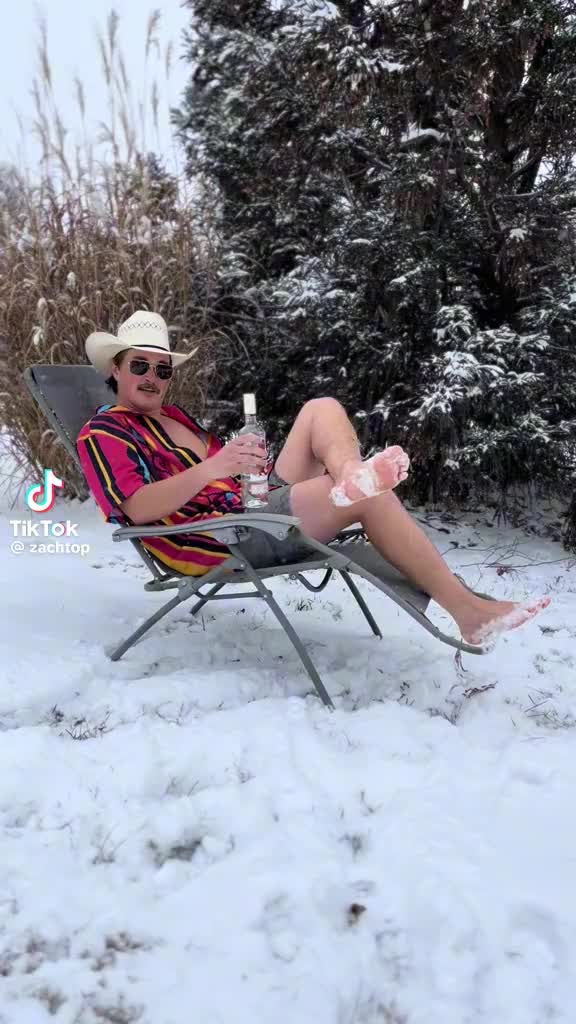 This may contain: a woman sitting in a lawn chair on top of snow covered ground