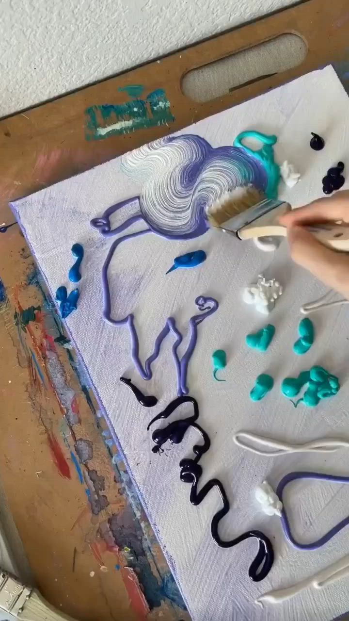 This may contain: someone is painting something with blue and purple colors on the paper while another person holds a paintbrush in their hand