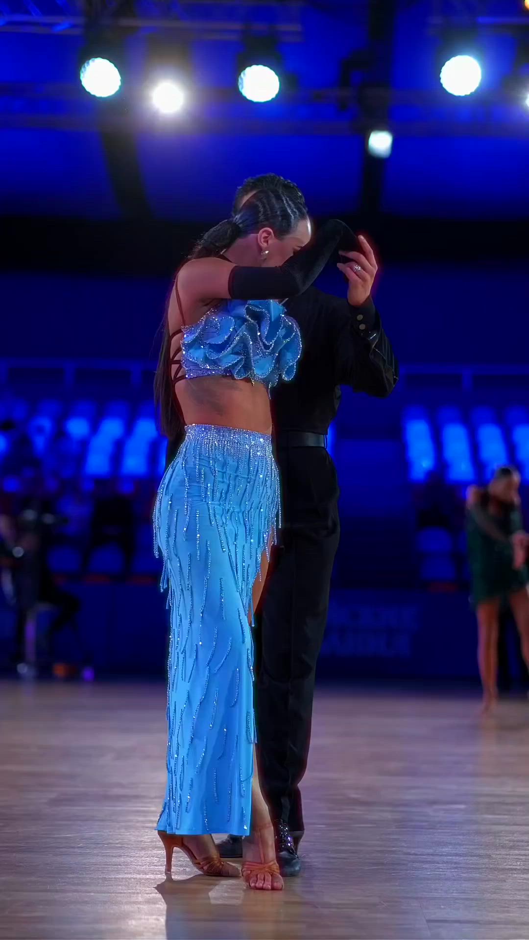 This may contain: a man and woman dancing on a dance floor