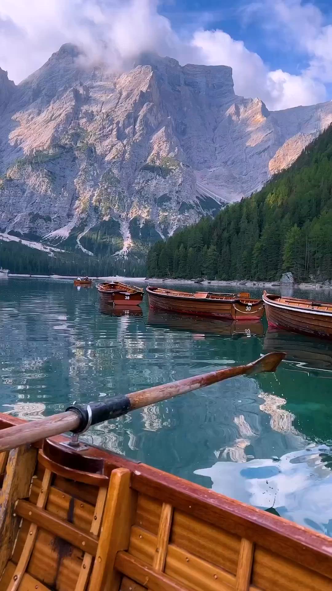 This may contain: there are many small boats in the water with mountains in the backgrouds